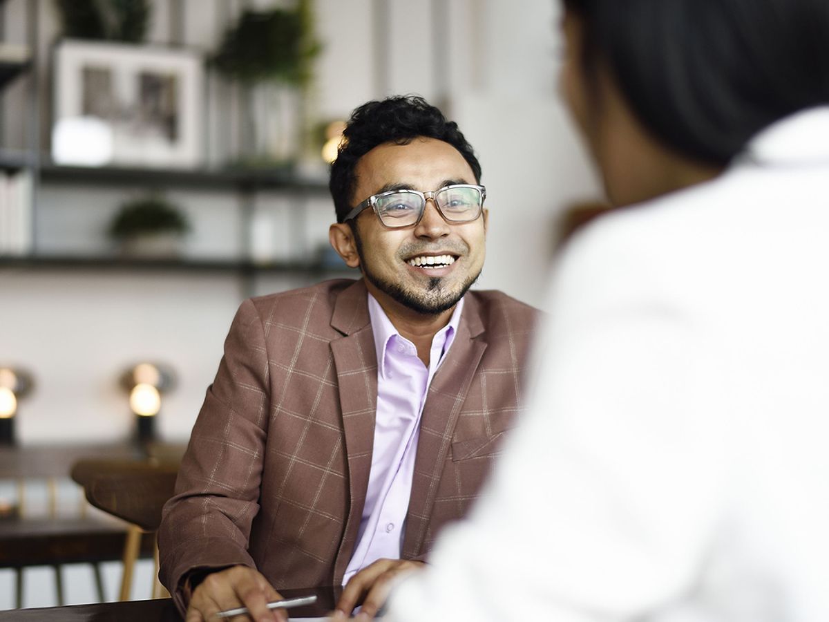 Business people smile as they discuss general liability insurance in an office.